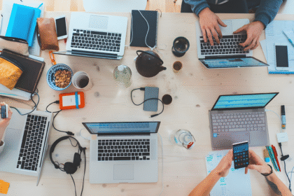 A group of people collaborating on laptops at a table, focused on a knowledge management guide.