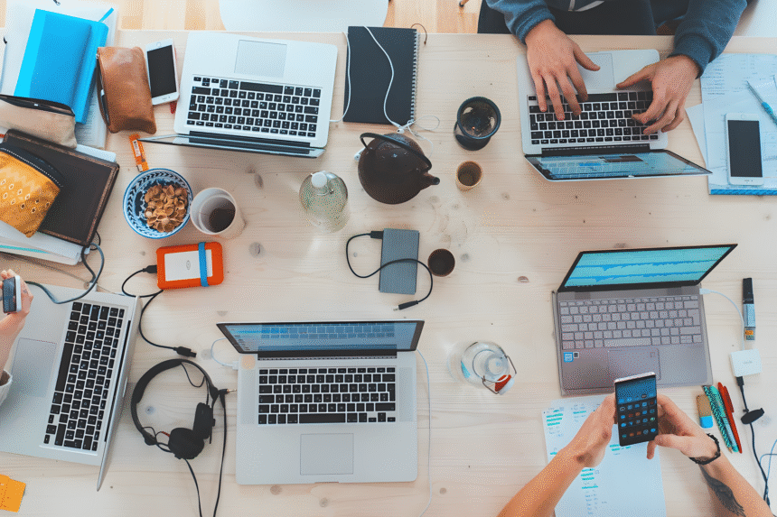 A group of people collaborating on laptops at a table, focused on a knowledge management guide.